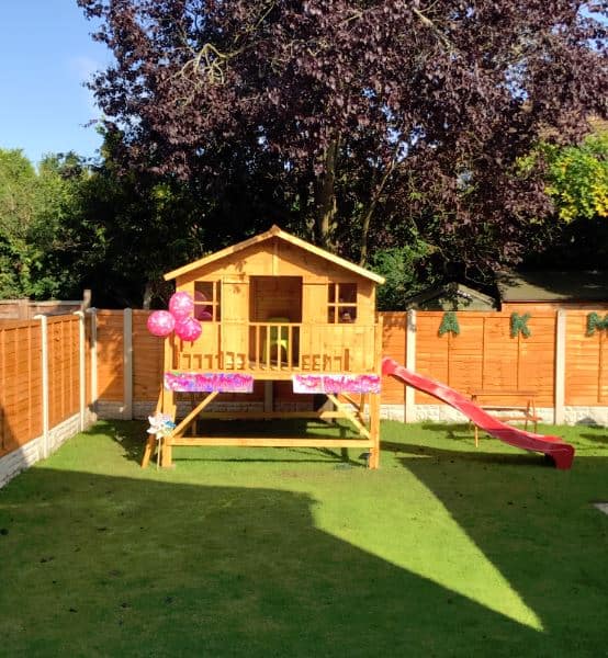 Wide wooden playhouse in a spacious grass garden