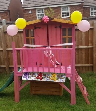 Bunny tower playhouse painted pink in a garden