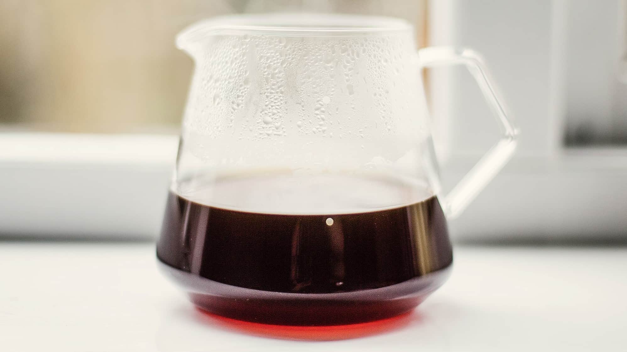 hot glass mug/jar of coffee steaming by a window