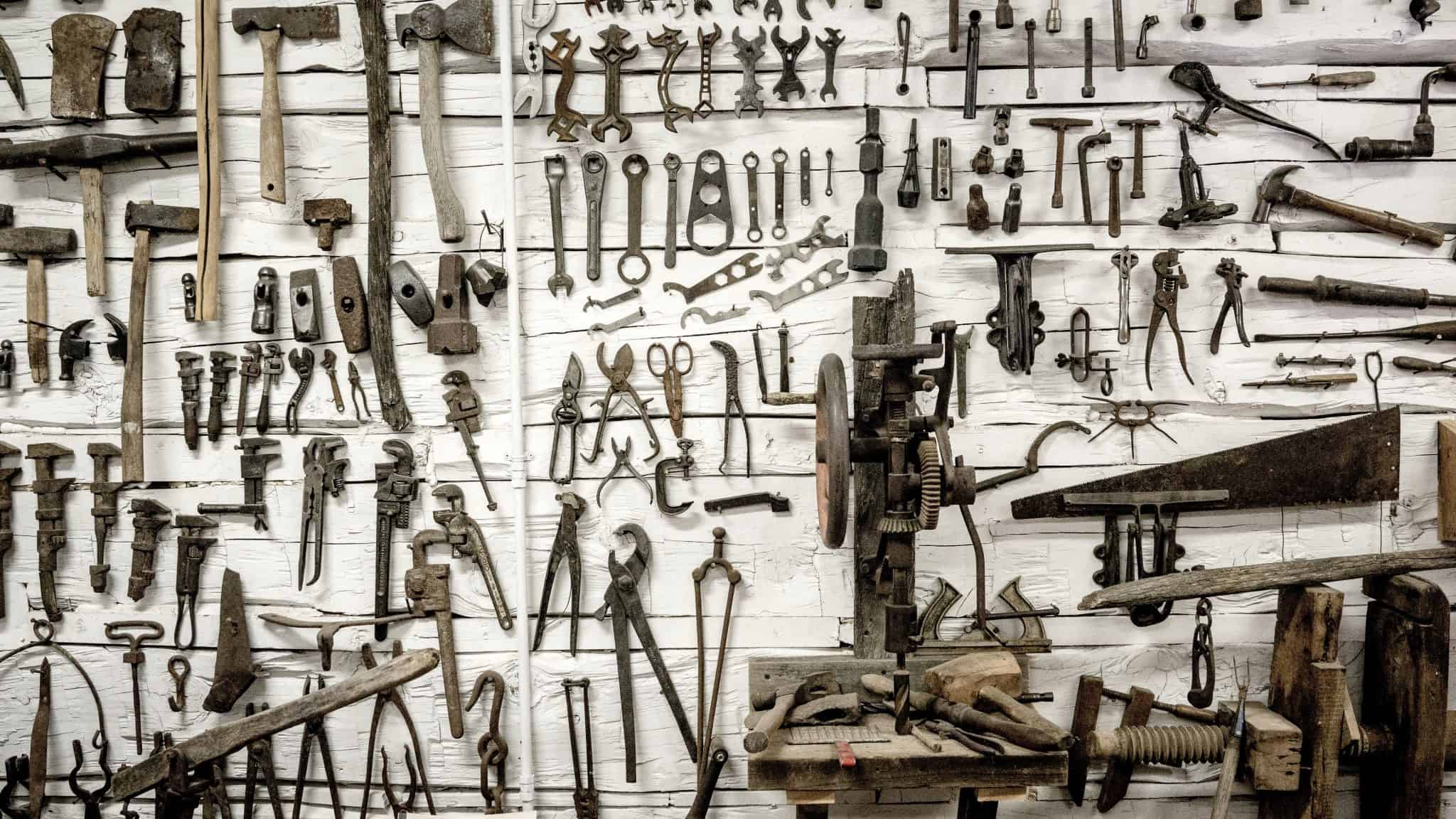 wall filled with various tools hung from it including axes and spanners